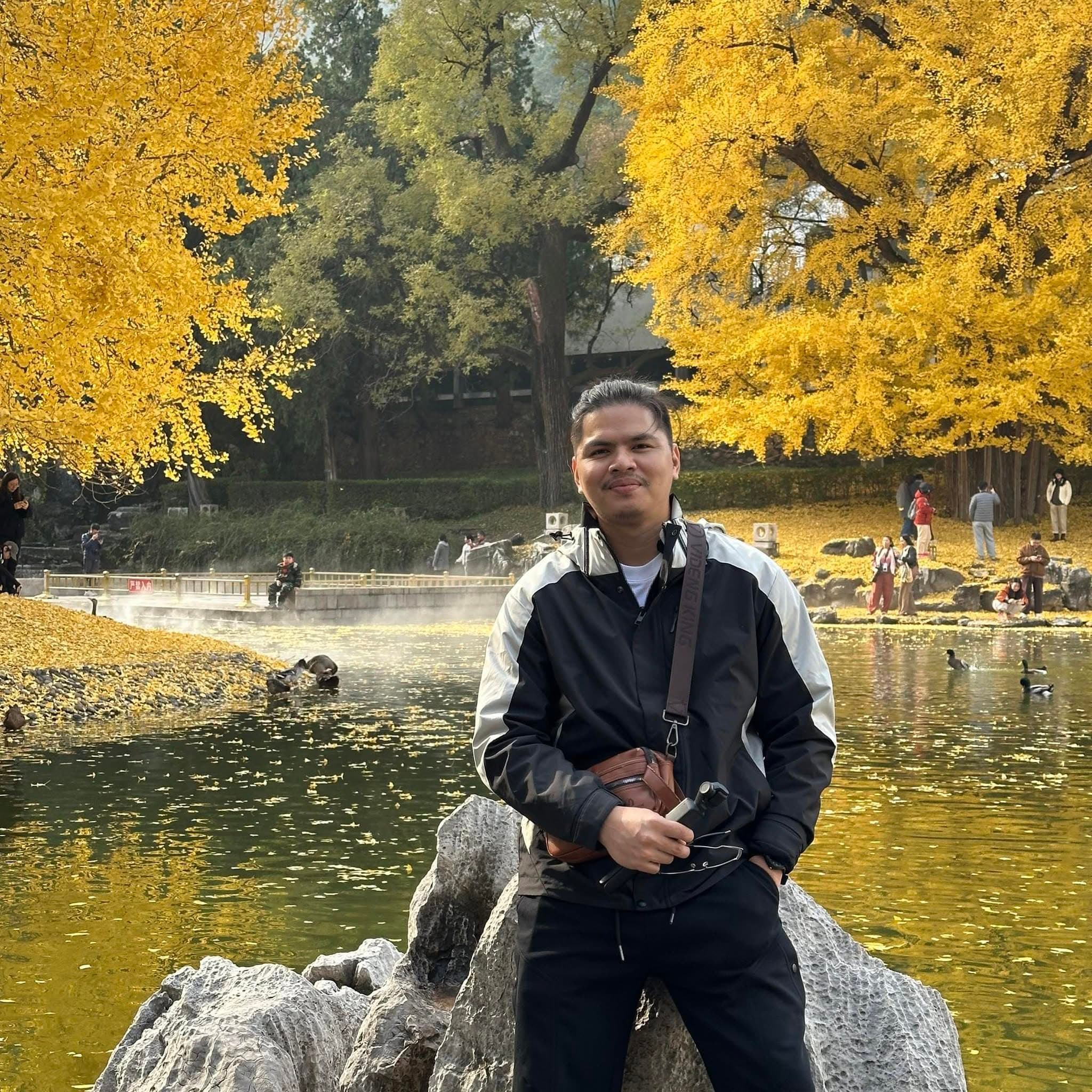 Jethro Arciaga in a park beneath autumn ginkgo trees